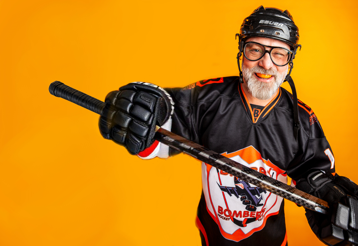 Mike in hockey gear holding a hockey stick.